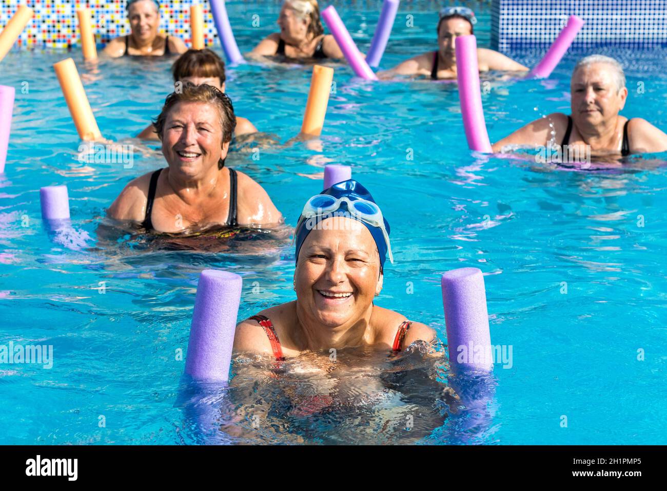 Gruppo di donne anziane attive che fanno acqua gym nella piscina esterna. Foto Stock