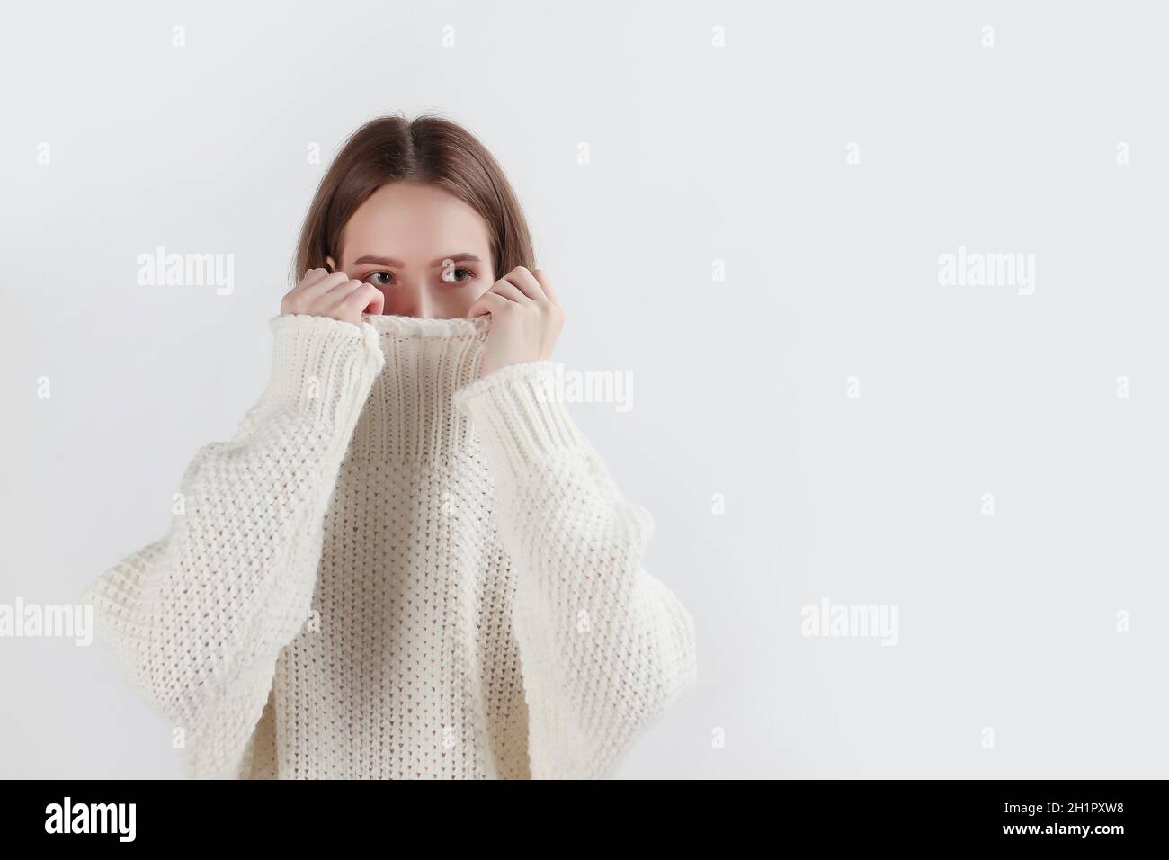 Una ragazza in un caldo maglione bianco con un lungo colletto. Il colletto  del maglione copre