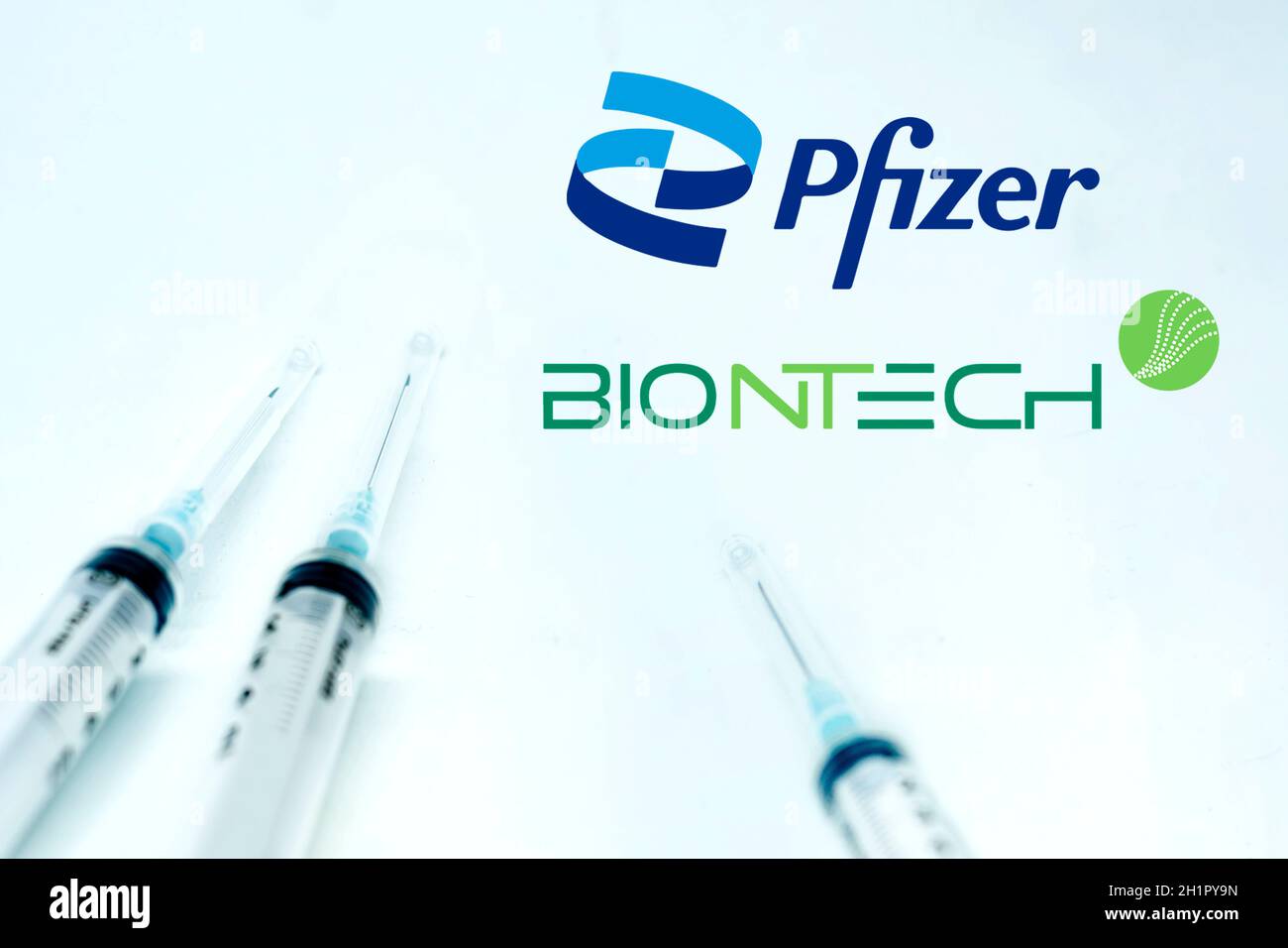 New York USA, 10 febbraio 2021: Tre siringhe accanto al logo Pfizer BioNTech isolate su sfondo bianco. Salute e prevenzione. Pfizer Biontech Foto Stock