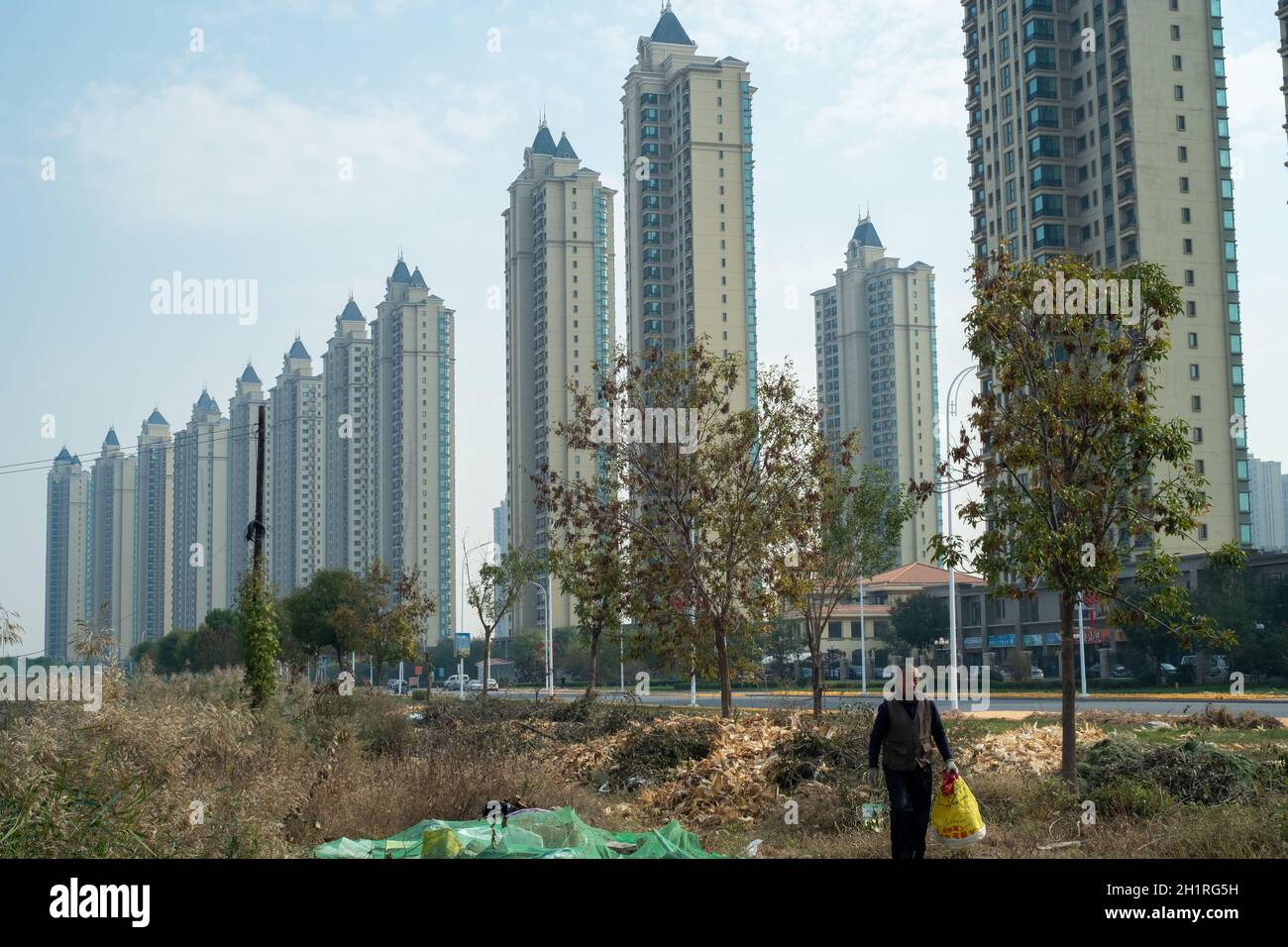 Un abitante anziano cammina di fronte alle proprietà residenziali Evergrande nel distretto di Wuqing, Tianjin, Cina. 19 ottobre 2021 Foto Stock