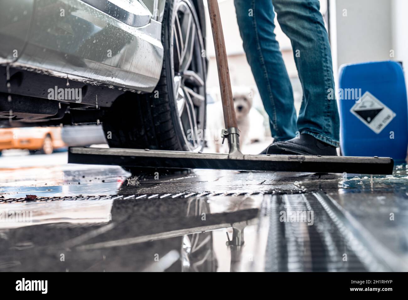Pulire il pavimento al lavaggio dell'auto con l'aiuto di una spatola d'acqua. Foto Stock