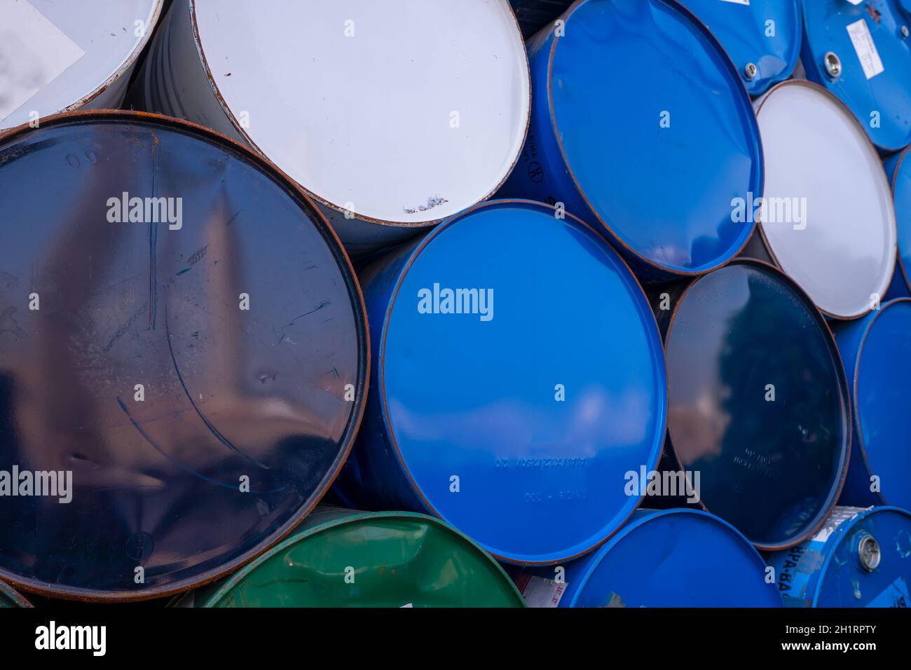 Vecchi barili chimici. Tamburo dell'olio blu, bianco e verde. Serbatoio dell'olio in acciaio. Magazzino dei rifiuti tossici. Contenitore per sostanze chimiche pericolose. Rifiuti industriali nel vecchio tamburo. Ha Foto Stock