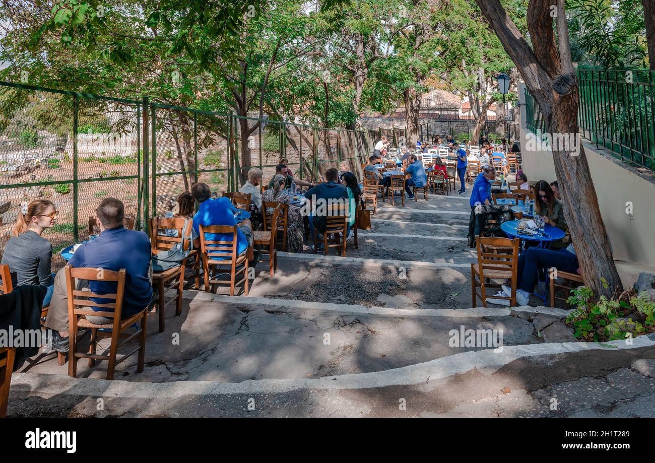 Le persone possono gustare dei rinfreschi in un tradizionale caffè greco all'aperto sul pendio della collina dell'Acropoli, nel quartiere di Plaka. Foto Stock