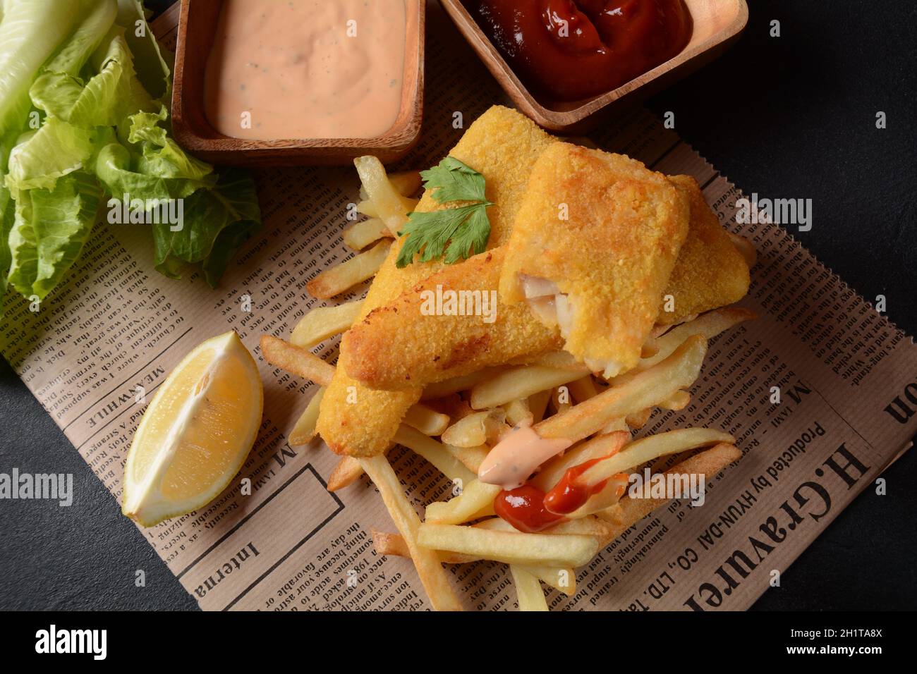 Cibo inglese tradizionale - Pesce e patatine. Filetti di pesce fritti e patatine fritte croccanti serviti con ketchup e salsa di torte fatte in casa. Foto Stock