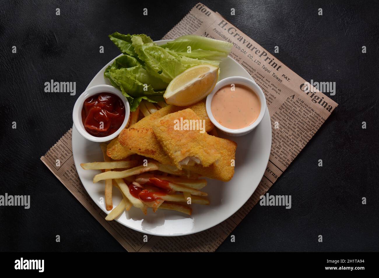 Cibo inglese tradizionale - Pesce e patatine. Filetti di pesce fritti e patatine fritte croccanti serviti con ketchup e salsa di torte fatte in casa. Foto Stock