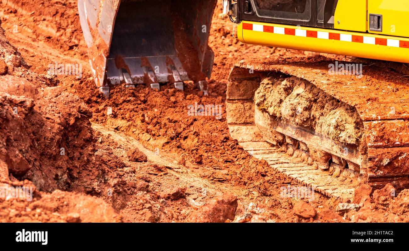 Retroescavatore che lavora scavando terreno in cantiere. Benna del terreno di scavo del retroescavatore. Escavatore cingolato che scavano su sporcizia. Macchina da scavo. Massa MOV Foto Stock