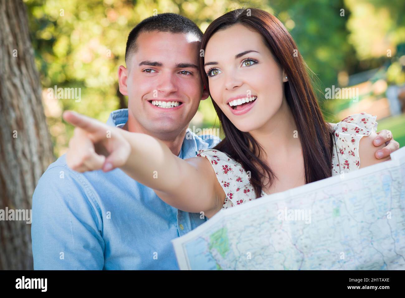 Felice razza mista giovane cerca su una mappa e i siti fuori insieme. Foto Stock