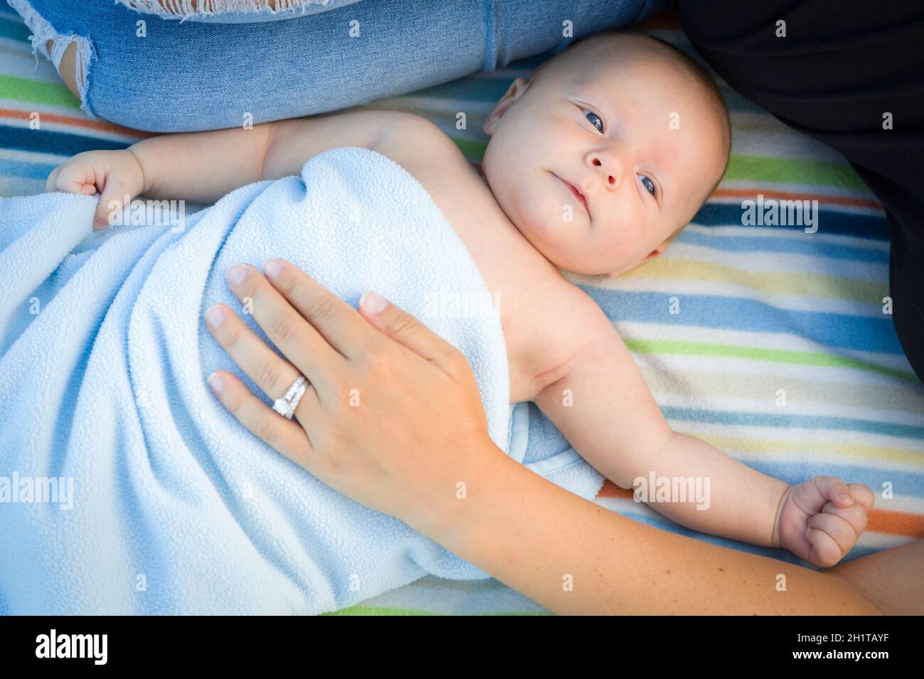 Splendido piccolo Bambino avvolto nella sua coperta in appoggio con la mamma. Foto Stock