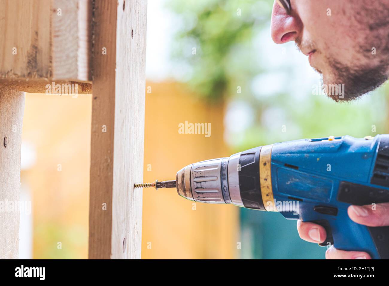 Fai da te l'handyman a casa sta usando un cacciavite cordless per l'avvitamento Foto Stock