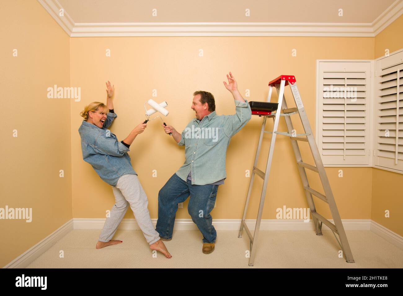 Divertimento giovane Riproduzione di spada lotta con i rulli di verniciatura in camera - scaletta e vassoio di vernice vicino a. Foto Stock