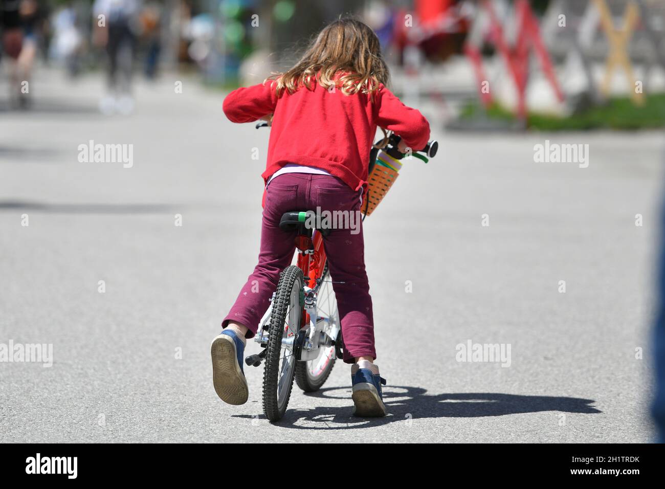 Ein kleines Kind auf einem Fahrrad auf der Esplanade in Gmunden bei Sonnenschein, Österreich, Europa - piccolo bambino in bicicletta sull'Esplanade in GM Foto Stock