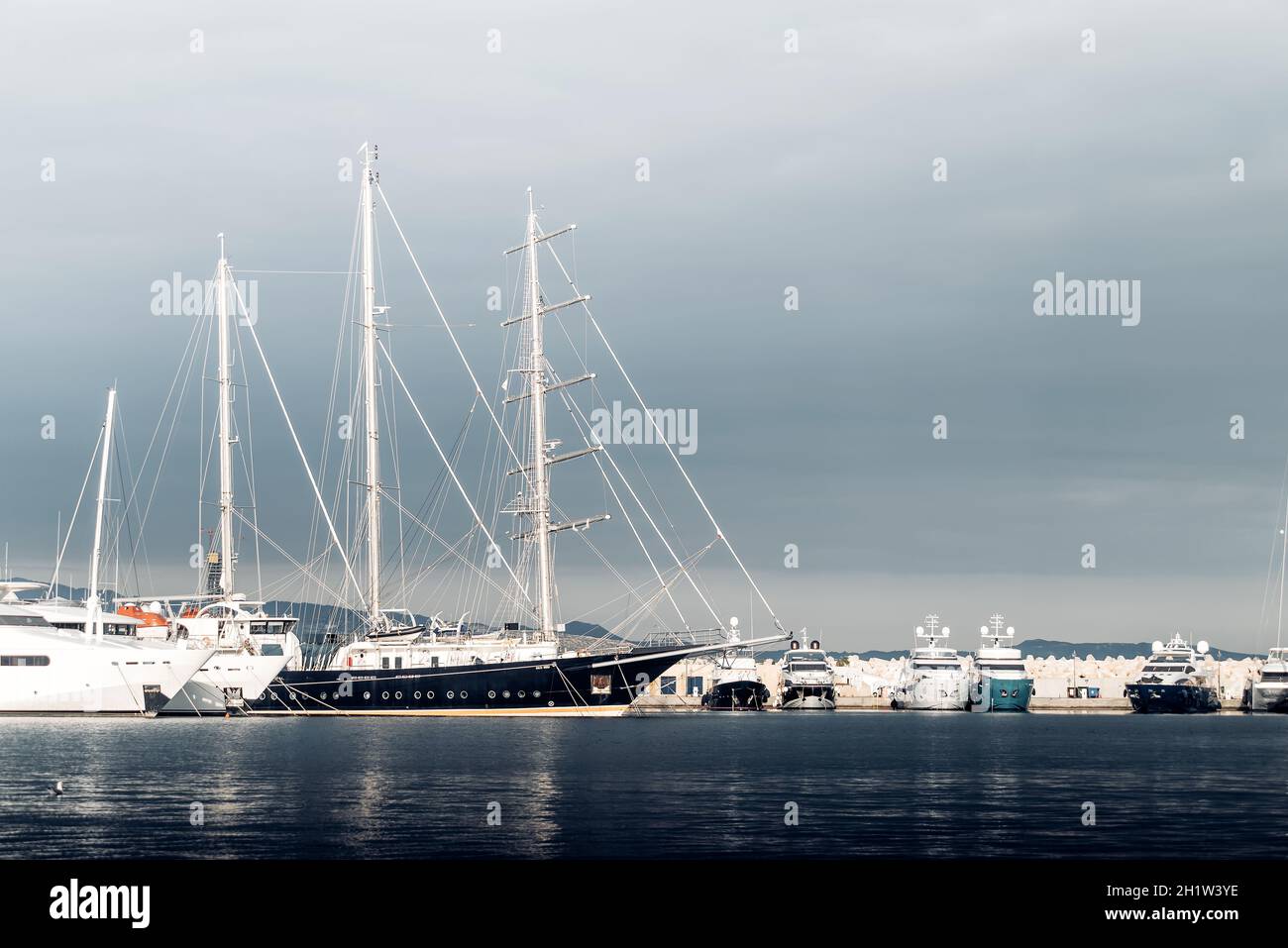 Grande yacht a vela tra gli yacht più piccoli del porto turistico Foto Stock