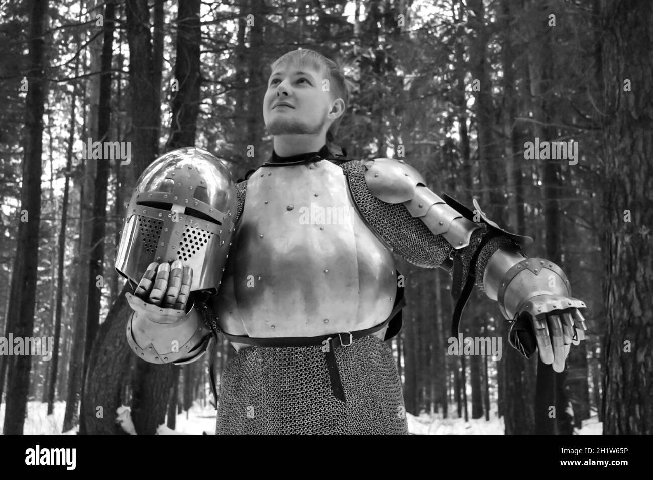 Cavaliere in armatura e con una spada nel mezzo di una foresta invernale. Divisa militare vintage. Foto Stock