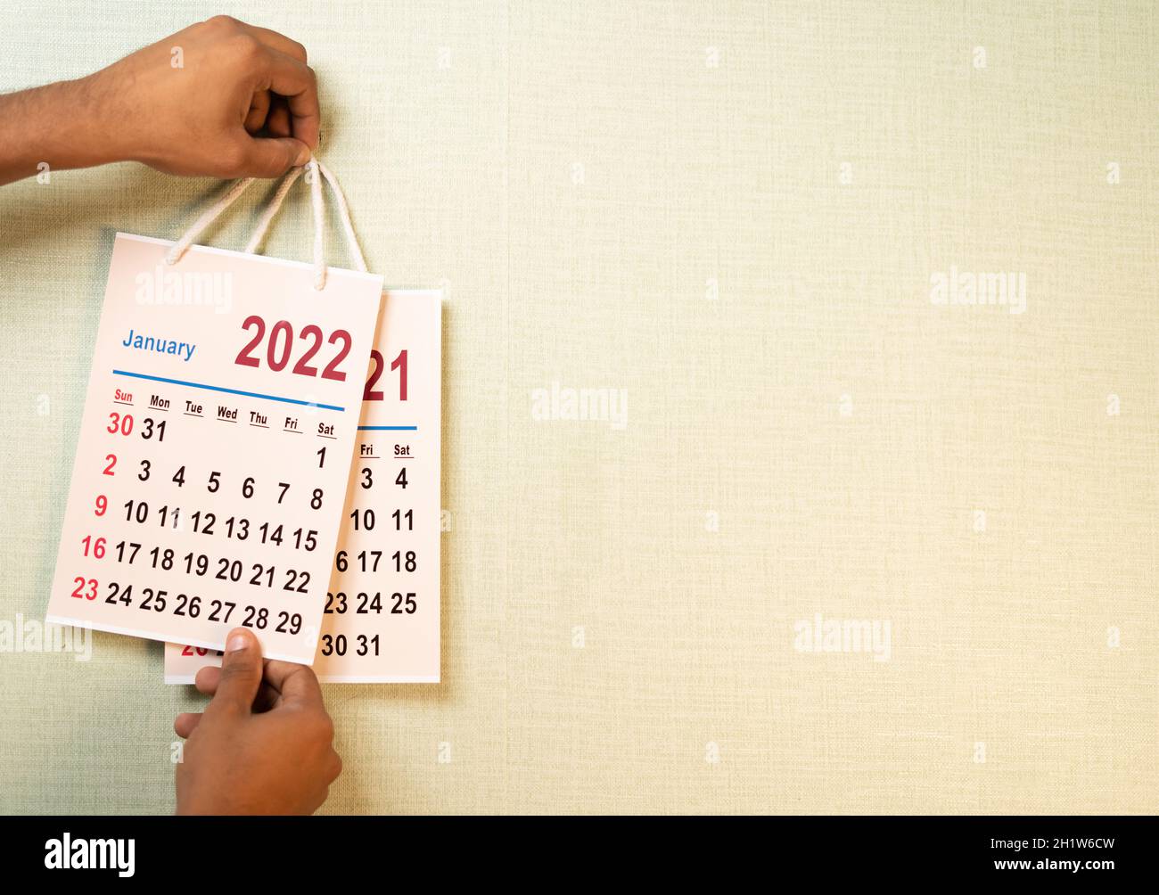 Primo piano colpo di mano che sostituisce 2021 vecchio calendario dal 2022 nuovo anno calendario sul muro - concetto di fine del 2021 o inizio del nuovo anno 2022 Foto Stock