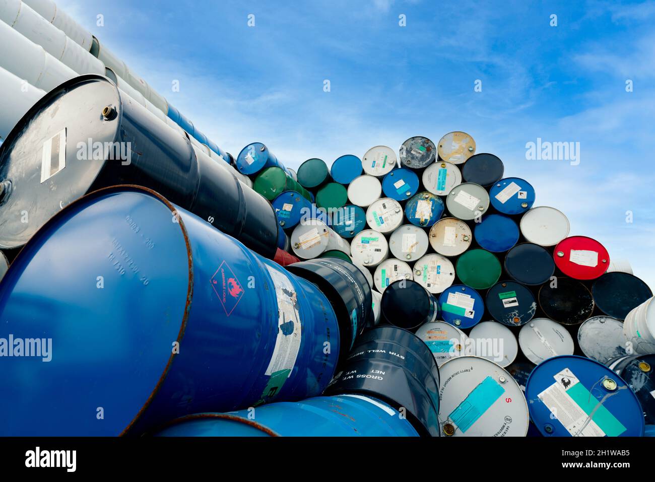 Vecchi barili chimici. Tamburo dell'olio blu con il simbolo del liquido infiammabile. Magazzino dei rifiuti tossici. Serbatoio per sostanze chimiche pericolose con etichetta di avvertenza. Rifiuti industriali in Foto Stock