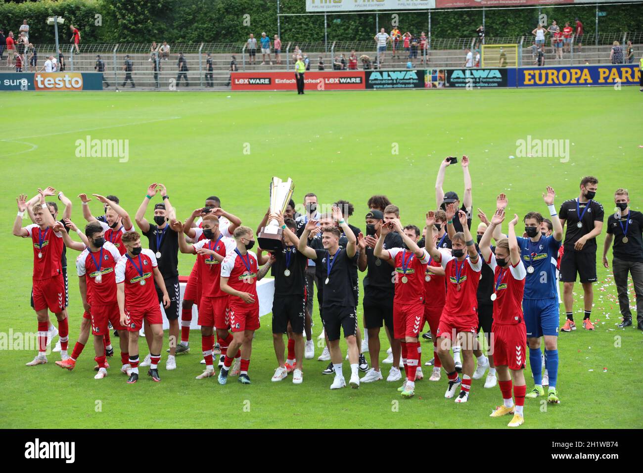 Die Spieler des SC Freiburg II und Trainer Christian Preußer bejuibeln mit dem Meisterpokal den Titel und Aufstieg in die dritte Fußball-Liga Foto Stock