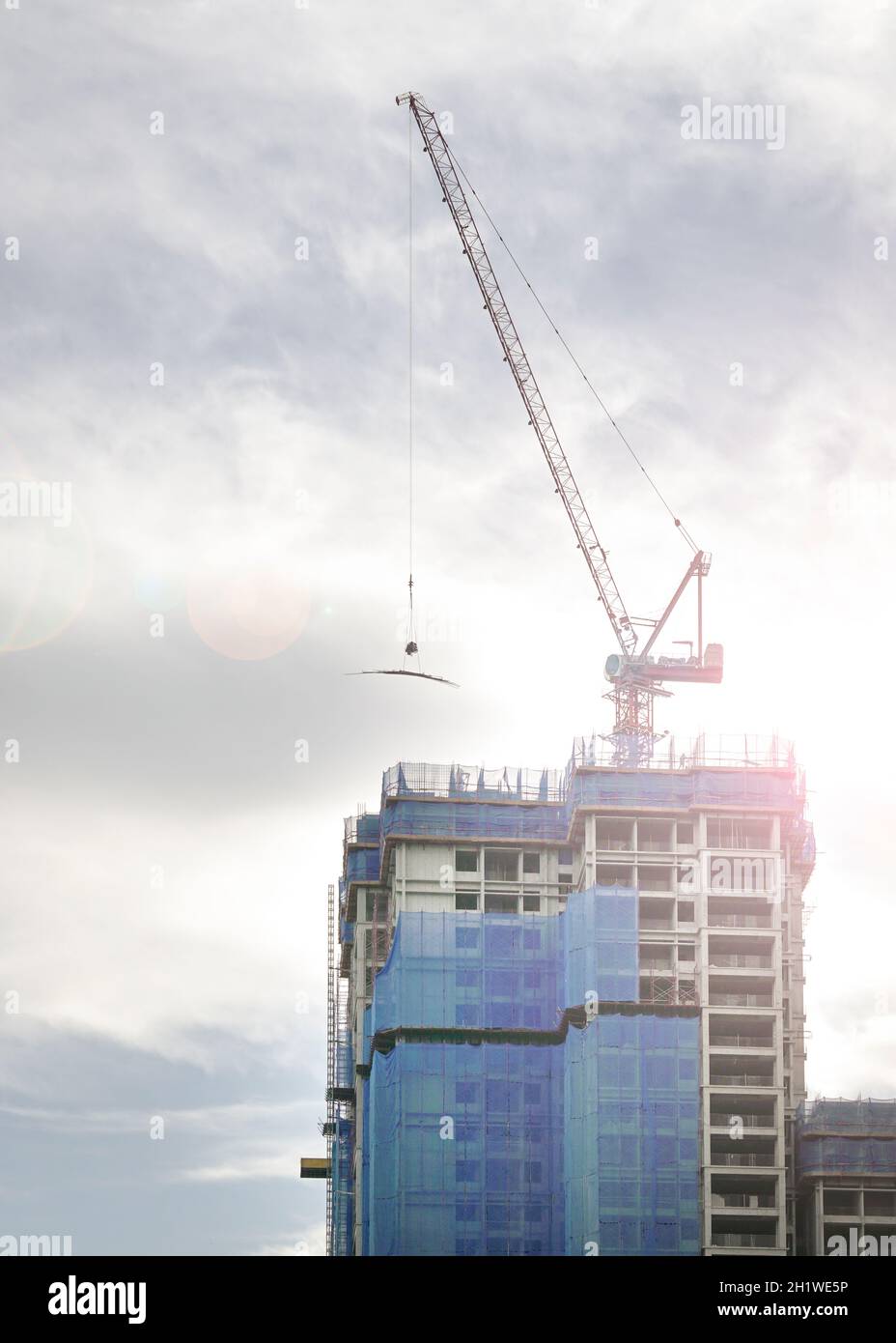 Alto edificio in costruzione con gru in cima. Spazio di copia. Foto Stock