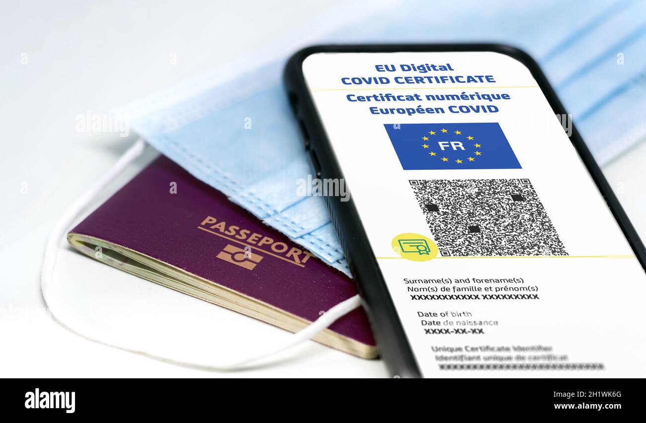 Certificato COVID digitale UE francese con il codice QR sullo schermo di un telefono cellulare su una maschera chirurgica e un passaporto francese. Immunità da Covid-1 Foto Stock