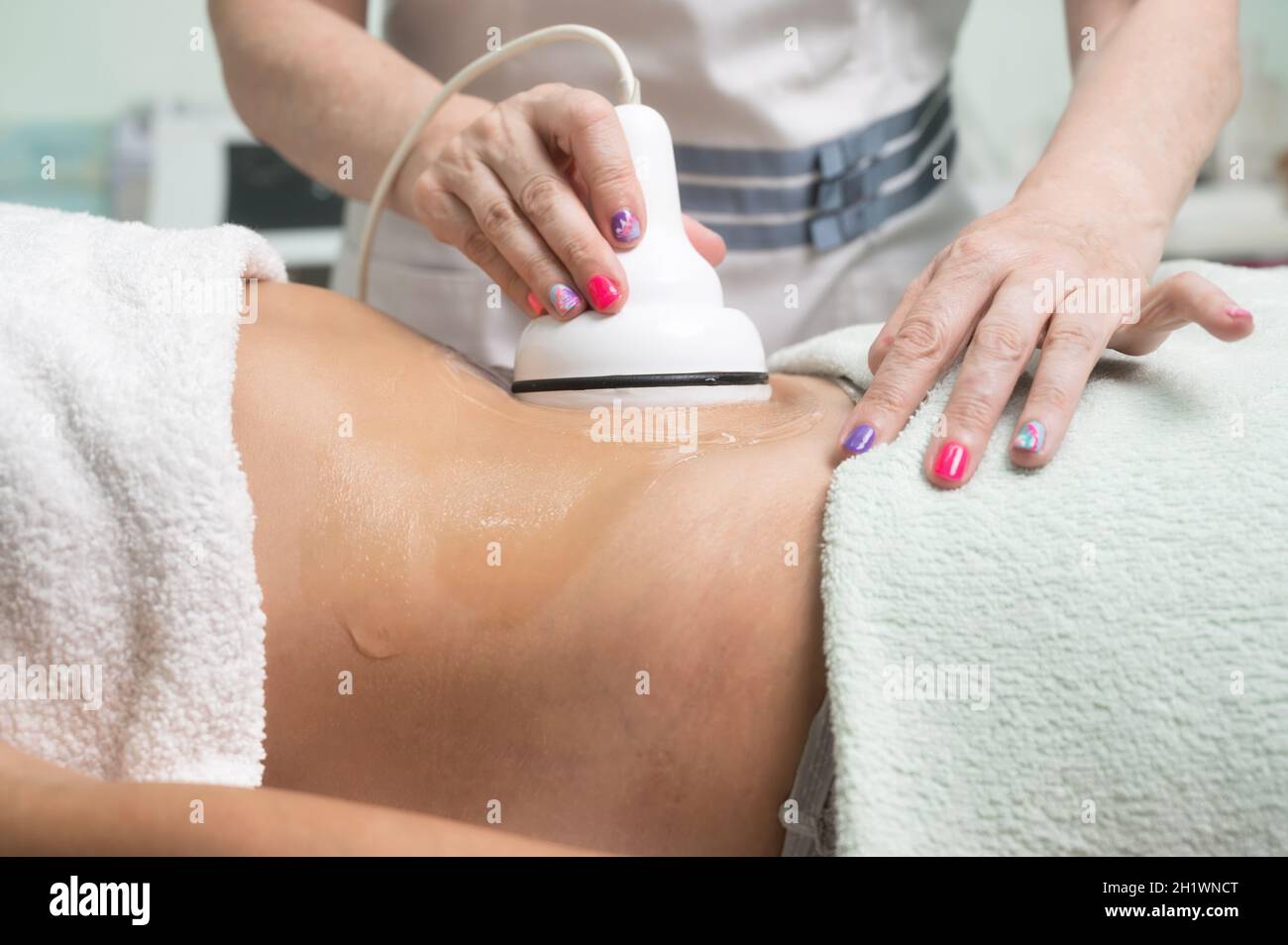 Donna che ottiene il trattamento di cavitazione ultrasonica da cosmetologist. Cliente femminile godendo di procedura anticellulite al salone di bellezza. Foto di alta qualità Foto Stock