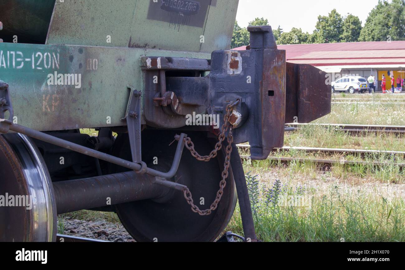 Treno su rotaie. Tecnologia obsoleta per l'adesione di carri ferroviari merci. Oliare il corpo del gancio di carico per l'aggancio. Un giunto per auto su rotaia che lo collega Foto Stock