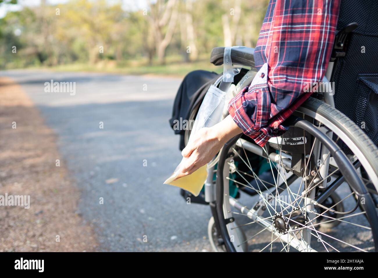 Donna asiatica di mezza età seduta su sedia a rotelle con borsa per le urine nel reparto ospedaliero, sano concetto medico Foto Stock