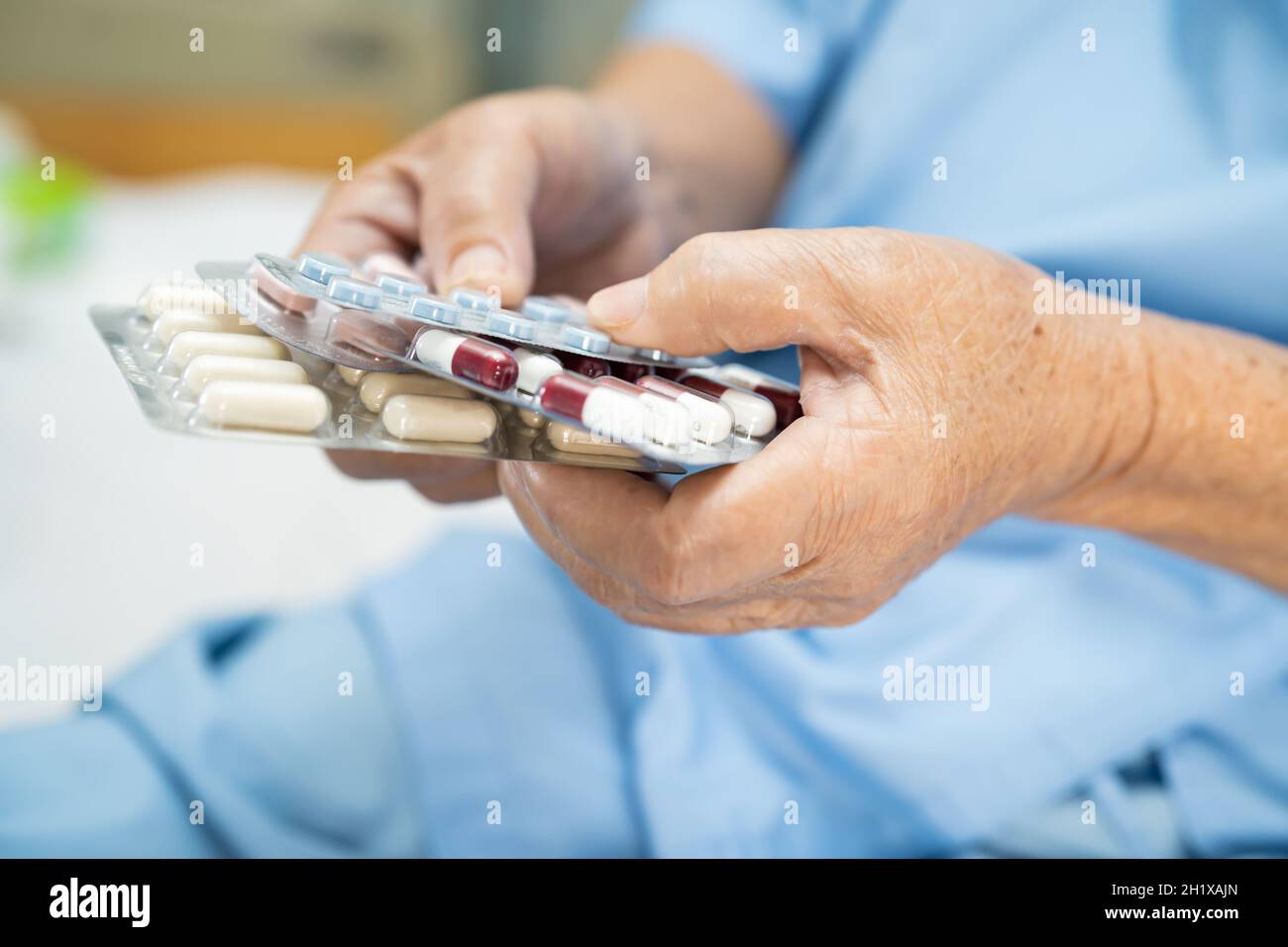 Anziano asiatico anziano o anziano donna anziana paziente che tiene antibiotici capsule pillole in blister imballaggio per il trattamento infezione paziente in ospedale; Pha Foto Stock