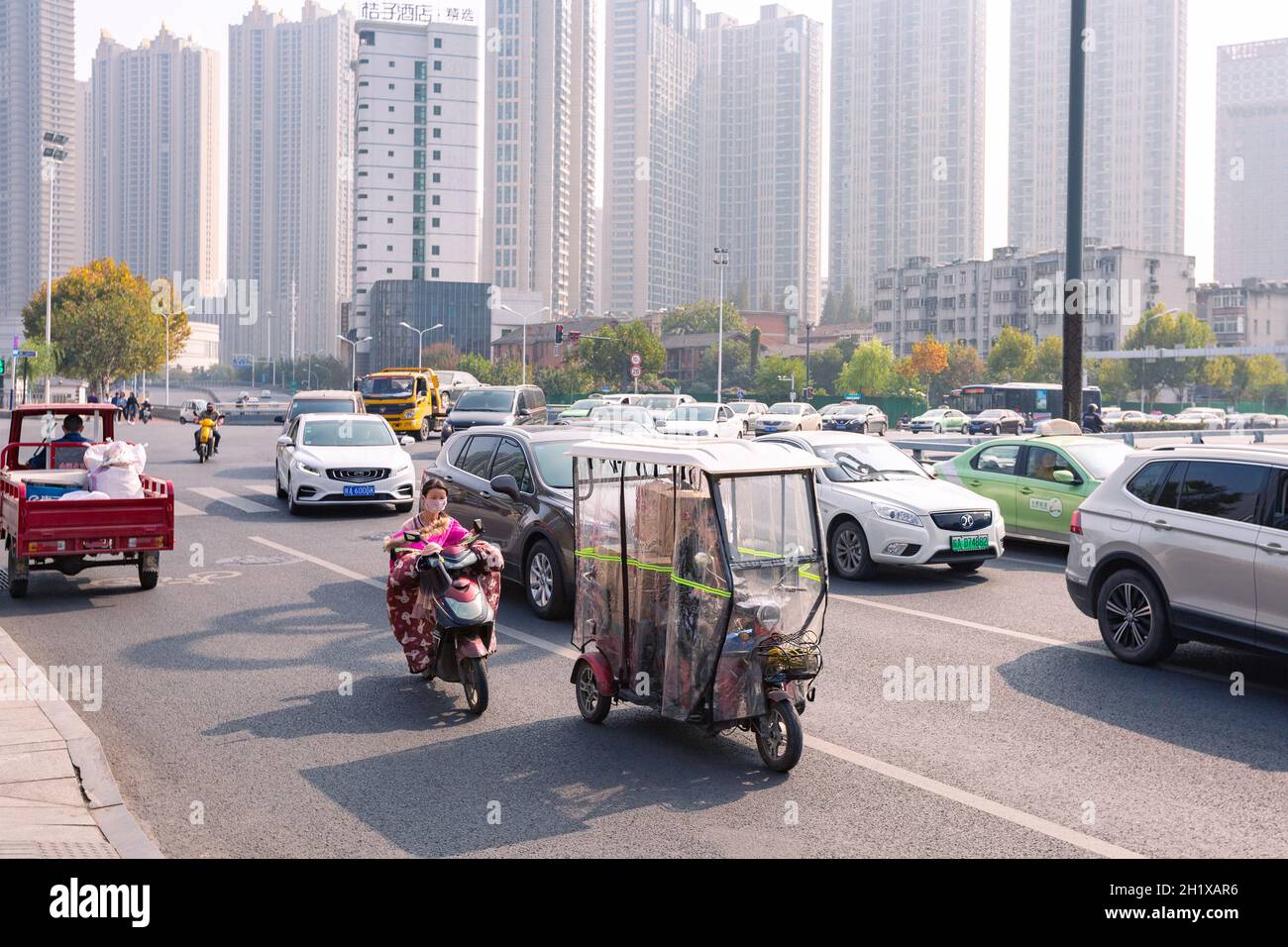 Hefei, Cina - 5 novembre 2019: Persone in bicicletta elettrica sul bivio. Il tempo divenne freddo e ogni bicicletta elettrica era dotata di vento colorato Foto Stock