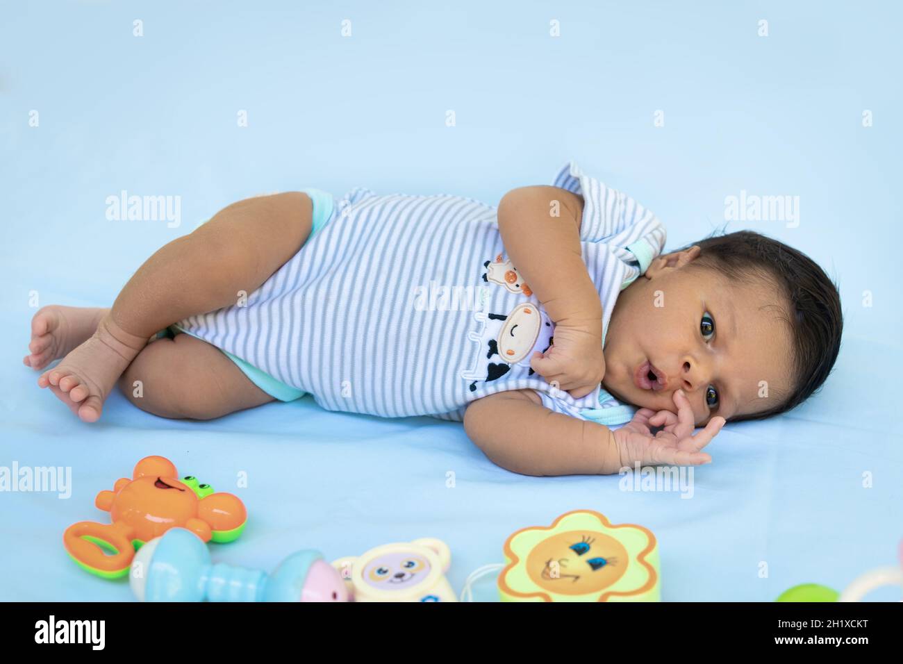 Immagine a tutta lunghezza di un bambino con gli occhi aperti adagiati su un panno blu Foto Stock