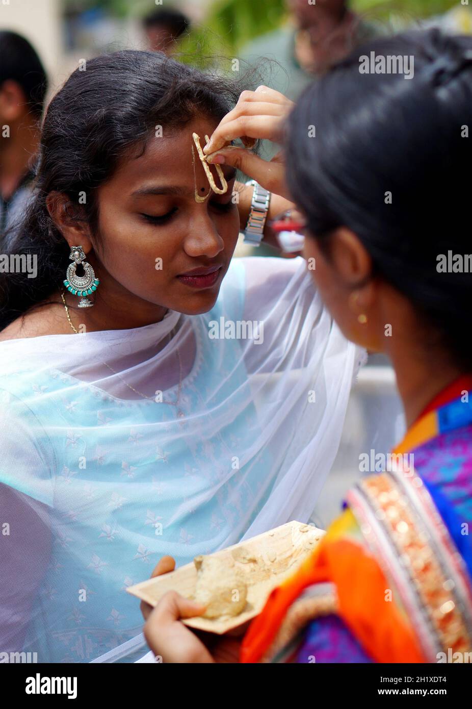 HYDERABAD,INDIA-AGOSTO 24,2019: Donna indù indiana applicare Tilak su testa anteriore di un devotee, un rituale religioso, sulla celebrazione del festival di Krisnastami in Dio Foto Stock