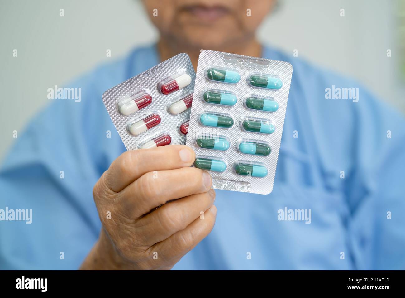 Asian anziano o anziano donna anziana paziente che tiene antibiotici capsule pillole in blister per trattamento infezione paziente in ospedale, Pha Foto Stock