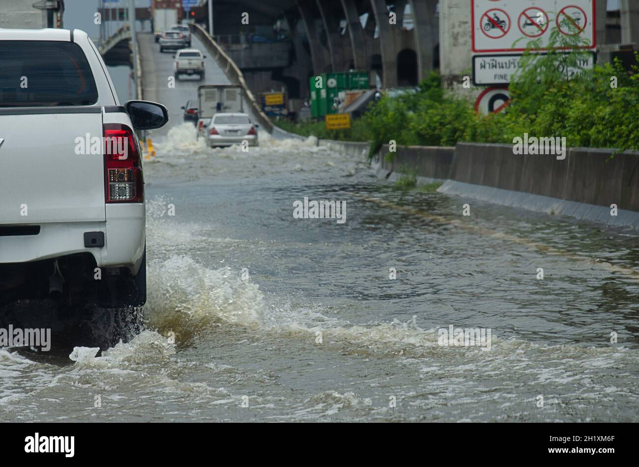 La pioggia battente allaga le strade della Thailandia. L'auto passa attraverso l'acqua allagata. Foto Stock
