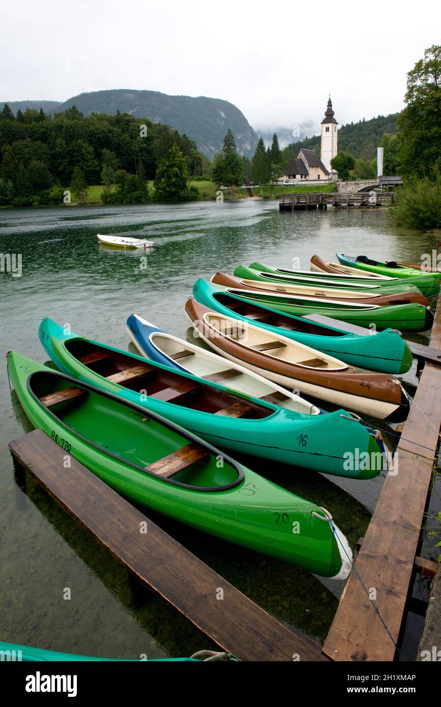 Canoe rivolta verso la chiesa dedicata a San Giovanni Battista in Ribcev Laz sul lago di Bohinj in Slovenia Foto Stock