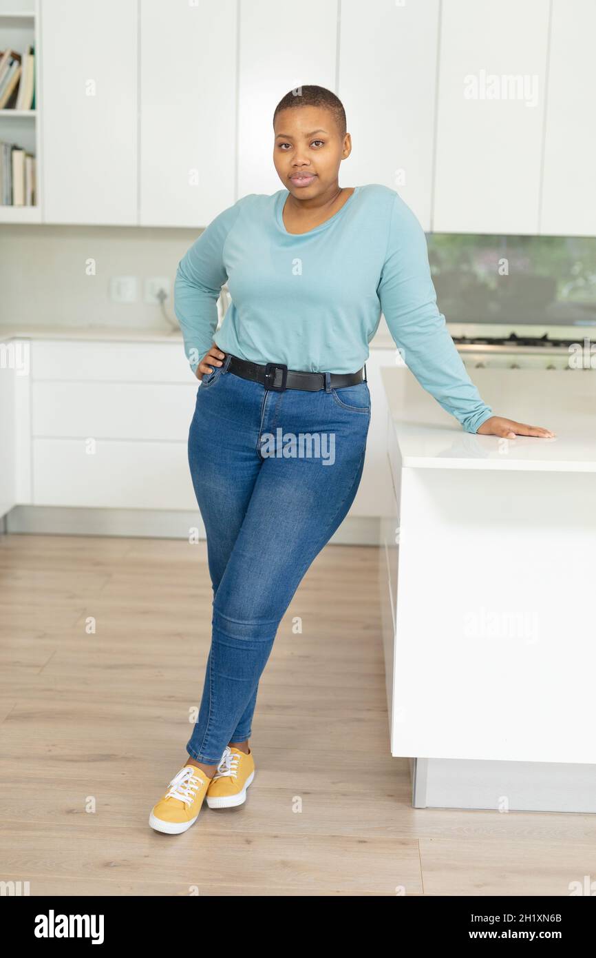 African american Plus taglia donna in piedi in cucina Foto Stock