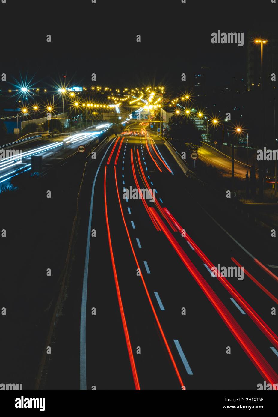Scatto verticale di un'autostrada e luci del veicolo sulla strada di notte Foto Stock