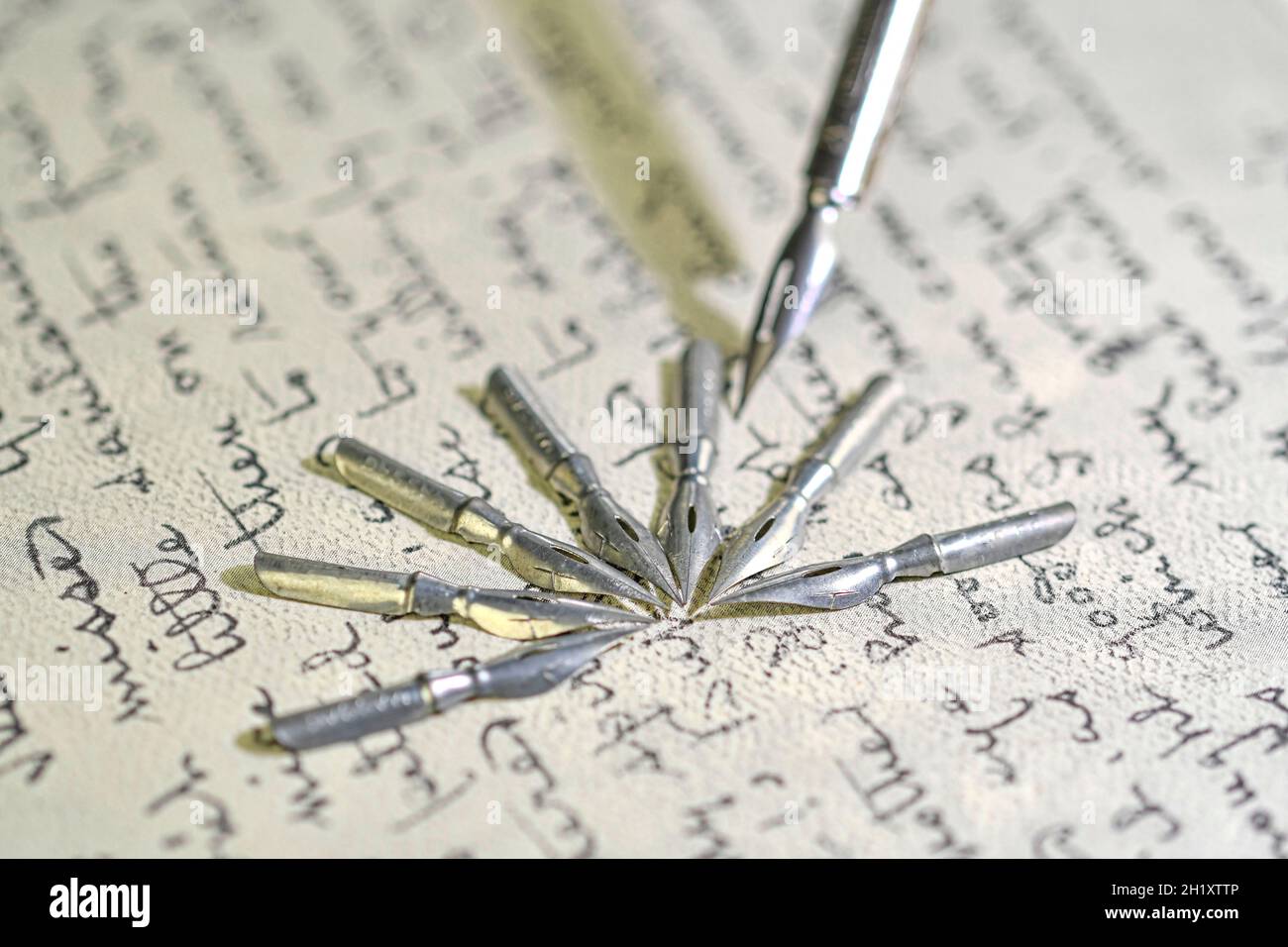 Primo piano di pennini metallici e vecchia penna sulla scrittura a mano vintage. Penna stilografica su un'antica lettera manoscritta. Vecchia storia. Stile retrò Foto Stock