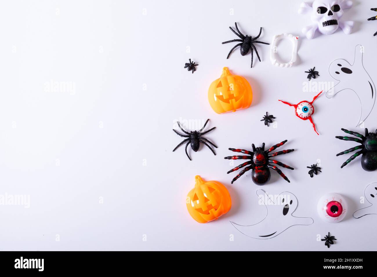 Composizione di decorazioni di Halloween con ragni, fantasma e zucca con spazio copia su bianco Foto Stock