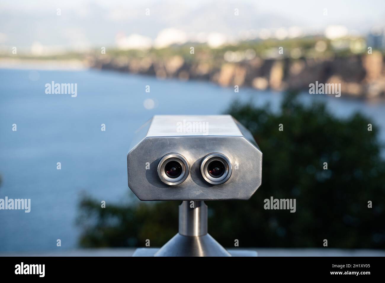 vista posteriore primo piano di binocoli in alluminio a gettoni con bel panorama del mare e delle montagne sullo sfondo Foto Stock