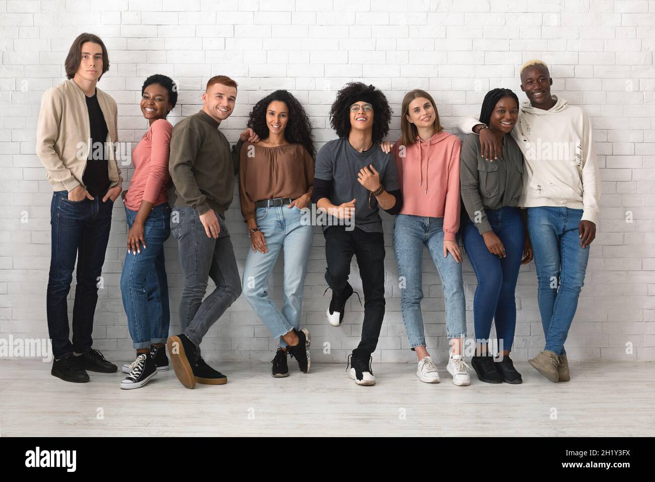 Gruppo multirazziale di giovani allegri che posano su bianco Foto Stock