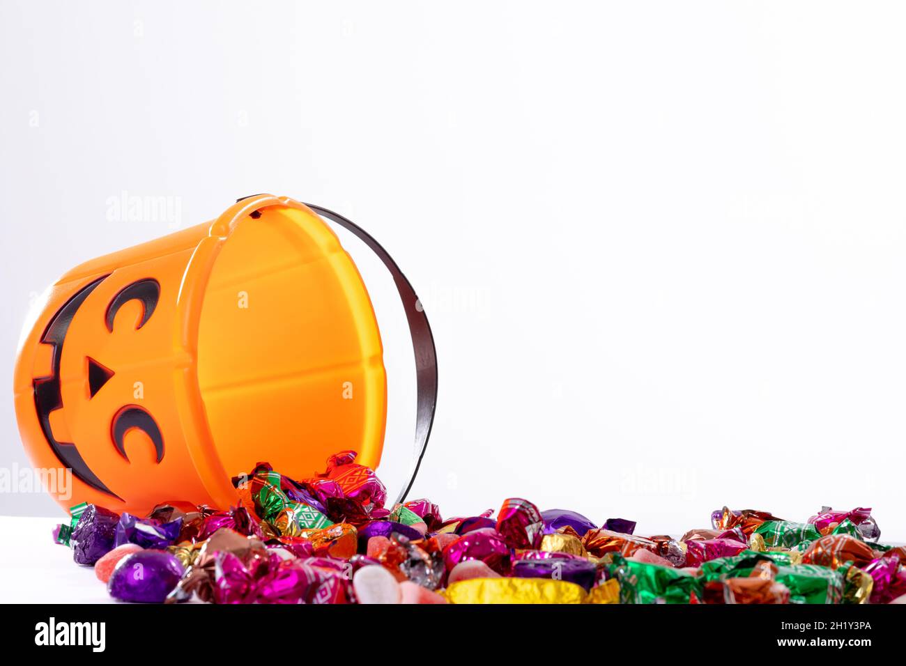 Composizione del secchio di Halloween con caramelle trick o treat su sfondo bianco Foto Stock