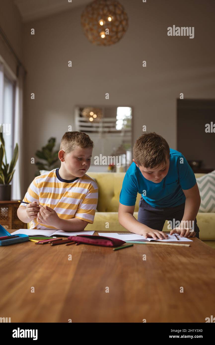 Due ragazzi caucasici che disegnano i loro libri nel soggiorno di casa Foto Stock