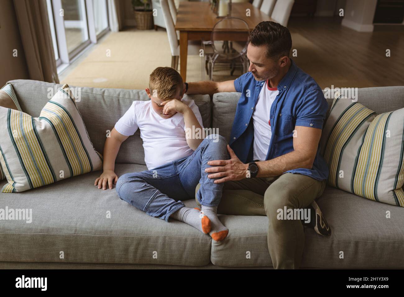 Il padre caucasico spaventa il figlio seduto sul divano di casa Foto Stock