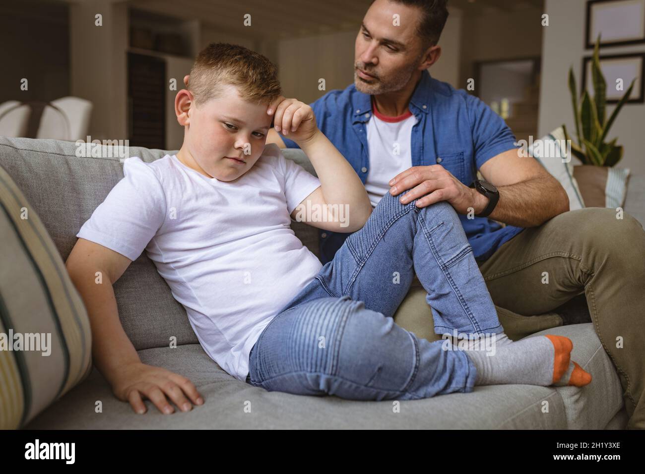 Il padre caucasico spaventa il figlio seduto sul divano di casa Foto Stock