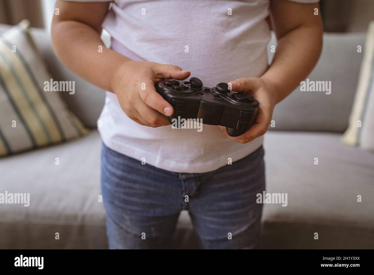 Metà sezione del ragazzo caucasico che tiene il controller del video gioco a casa Foto Stock