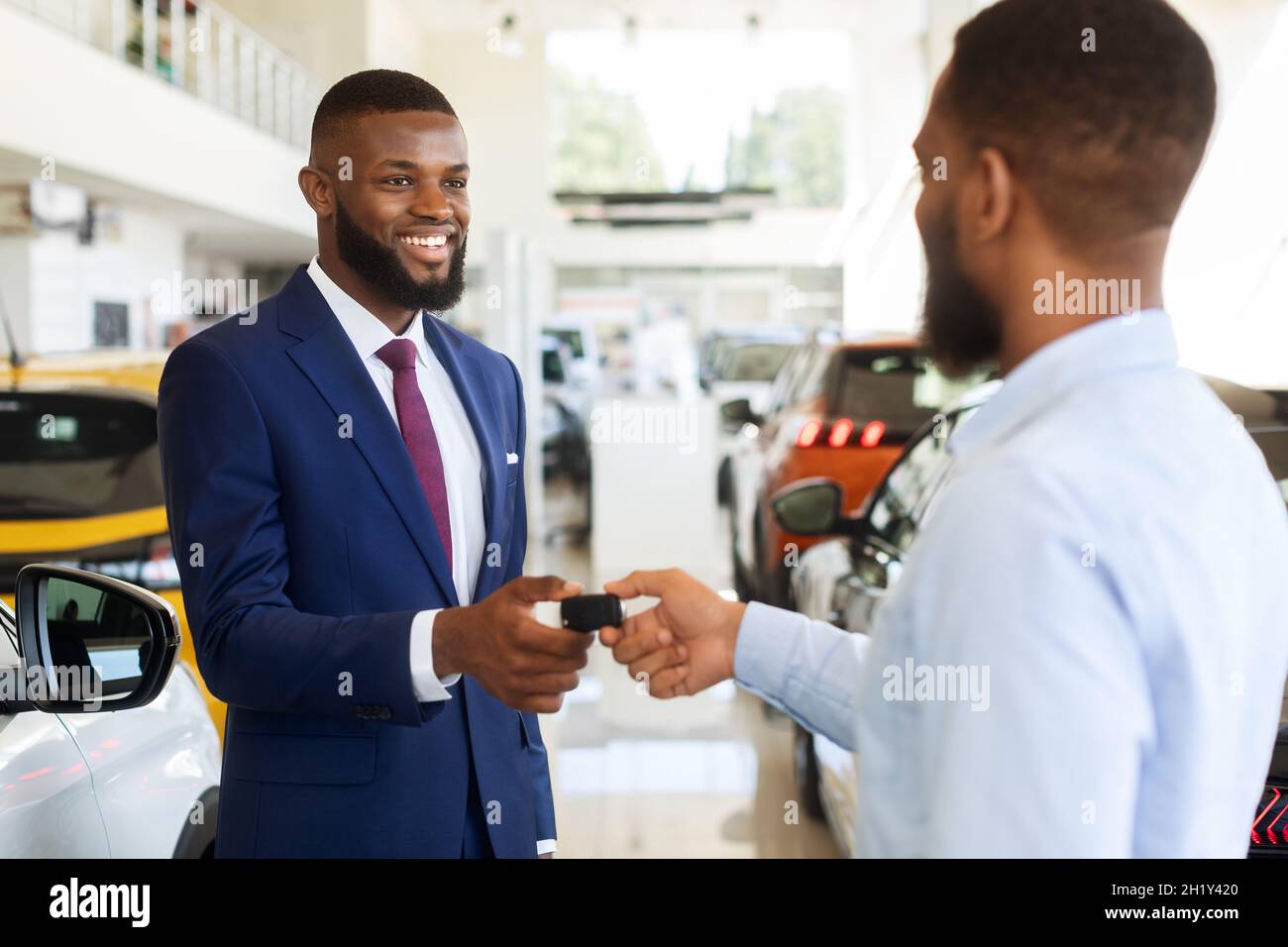 Vendita o noleggio auto. Black Manager che dà le chiavi al cliente maschio, Closeup Foto Stock