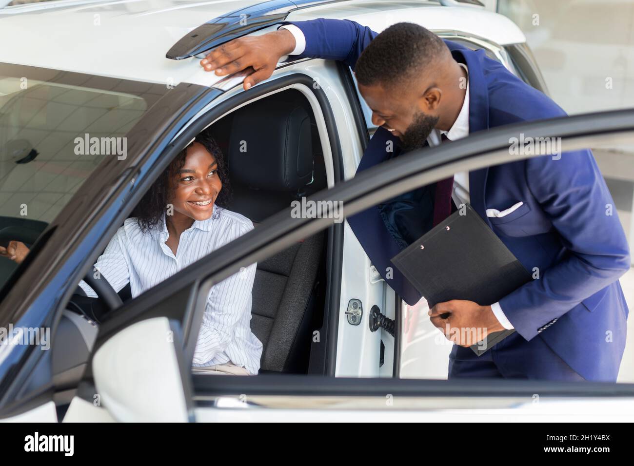 Black Manager professionale in Auto Showroom Consulenza cliente femminile seduto in auto Foto Stock
