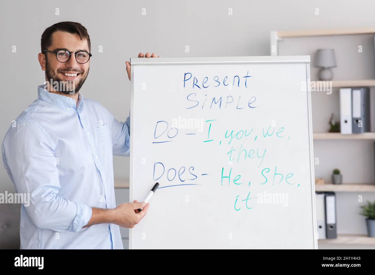 Amichevole felice uomo caucasico maturo insegnante in occhiali sparando lezione online che punta a lavagna in salotto Foto Stock