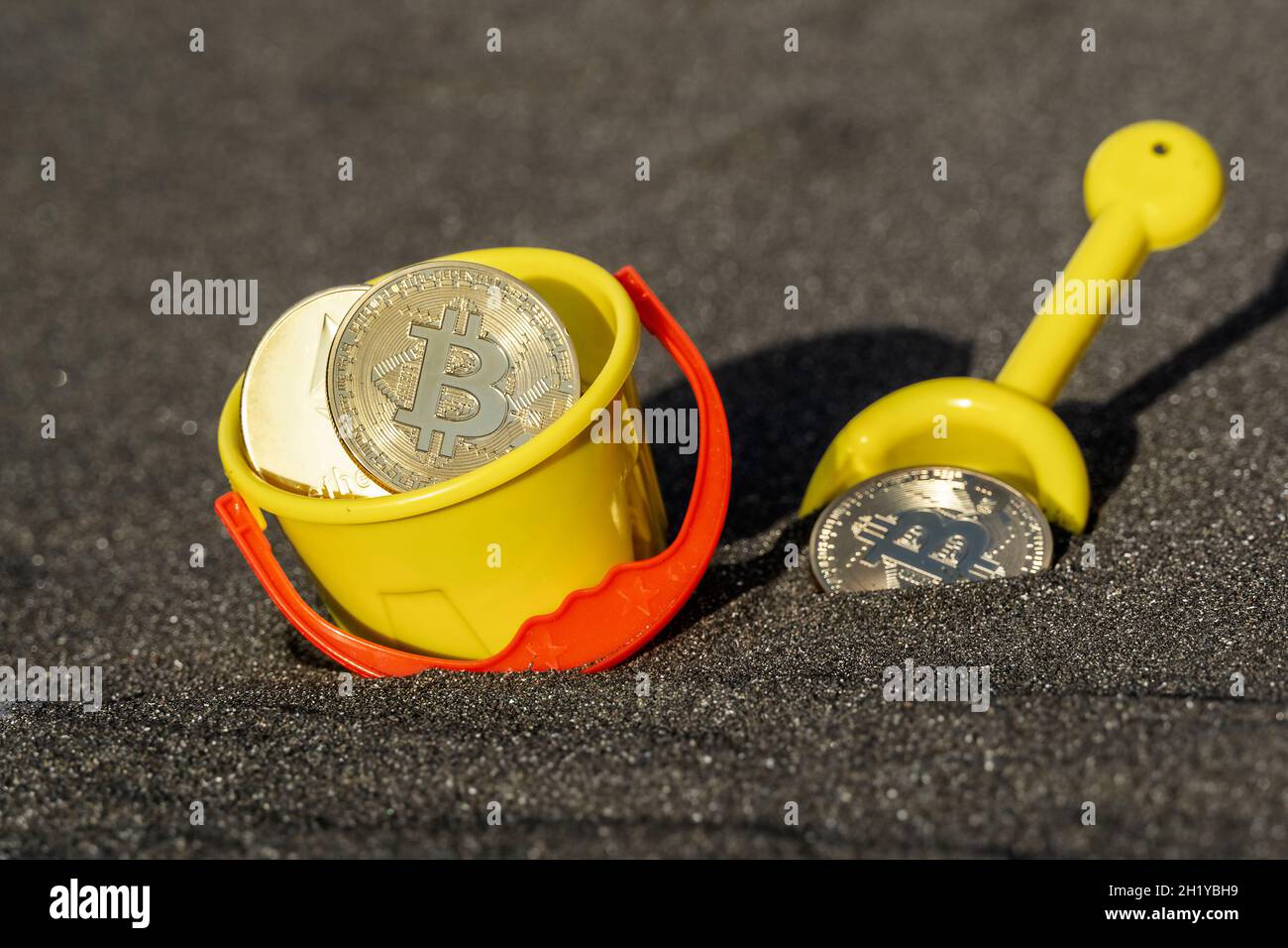 Monete delle valute digitali Bitcoin ed Ethereum con secchio e pala nella sabbia Foto Stock