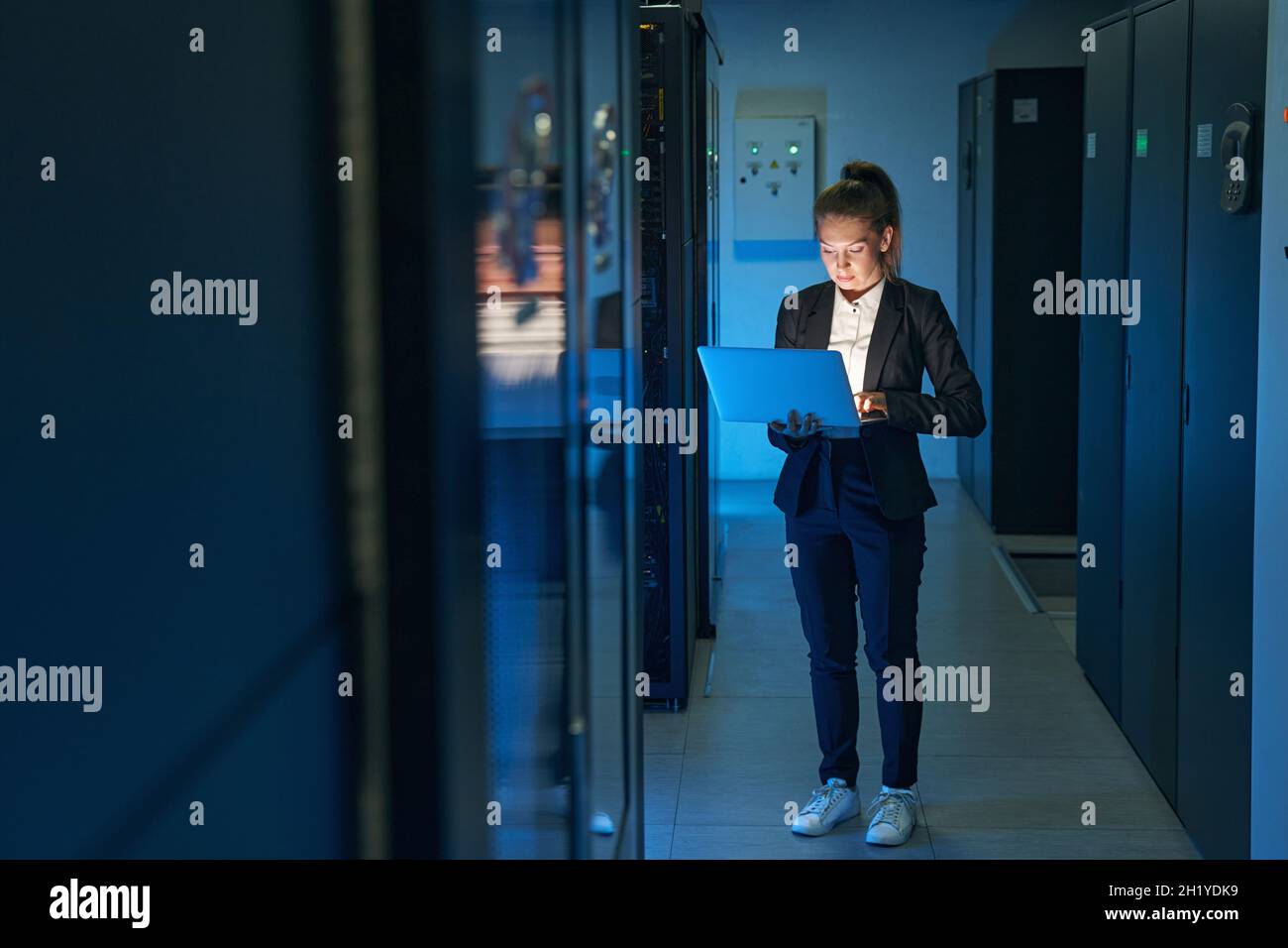 Tecnico femminile che utilizza il laptop per analizzare il server nel data center Foto Stock