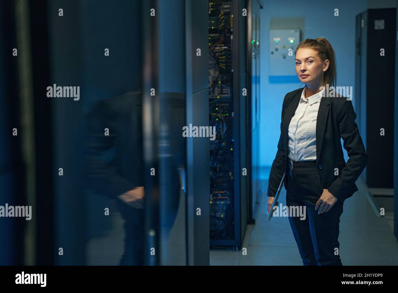Ingegnere donna affidabile in piedi vicino ai rack server nel data center Foto Stock