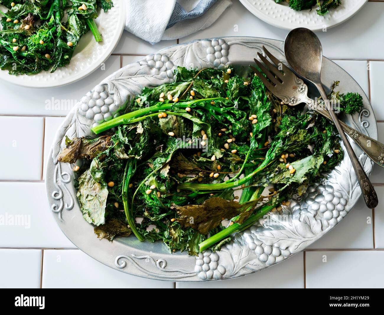 Broccolini fritti con pinoli su un piatto d'annata Foto Stock